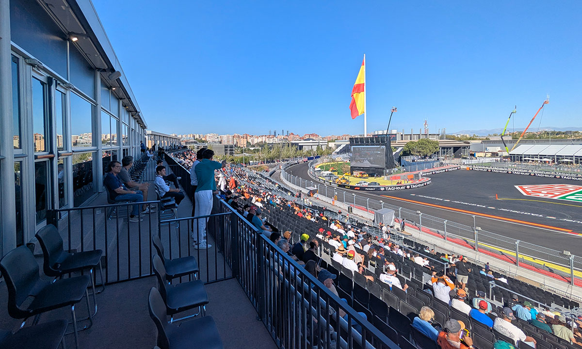 Madring-F1-circuit-LDA-references-07 Spectators overlooking MADRING from a hospitality balcony, with grandstands and a Spanish flag beyond